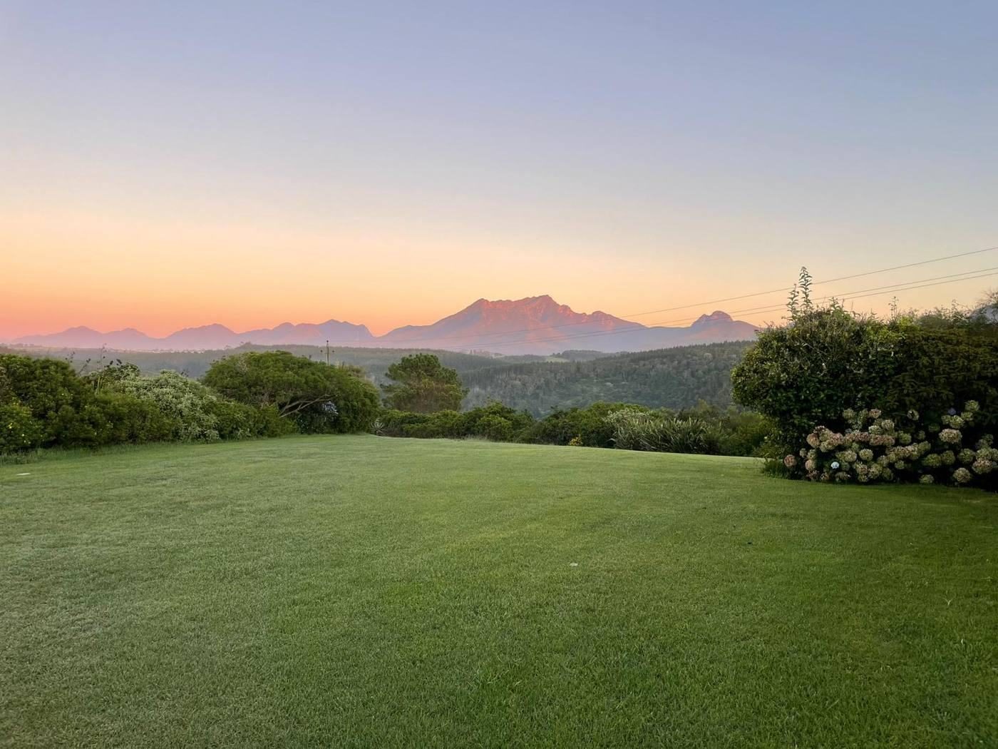 Dusk over the Outeniqua mountains seen across a green lawn
